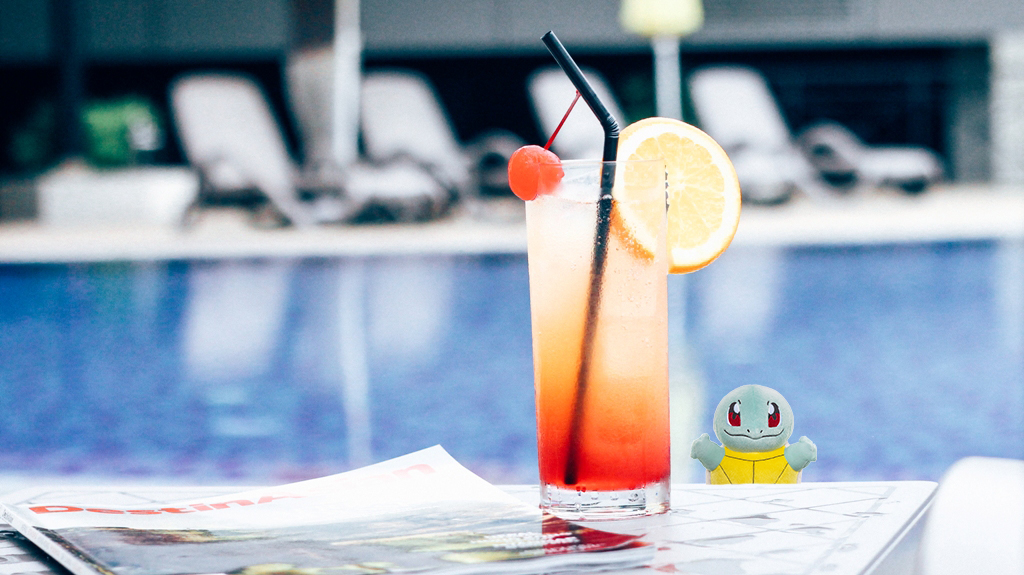 Picture of a cocktail and a newspaper next to the pool at the Airport Transit Hotel
